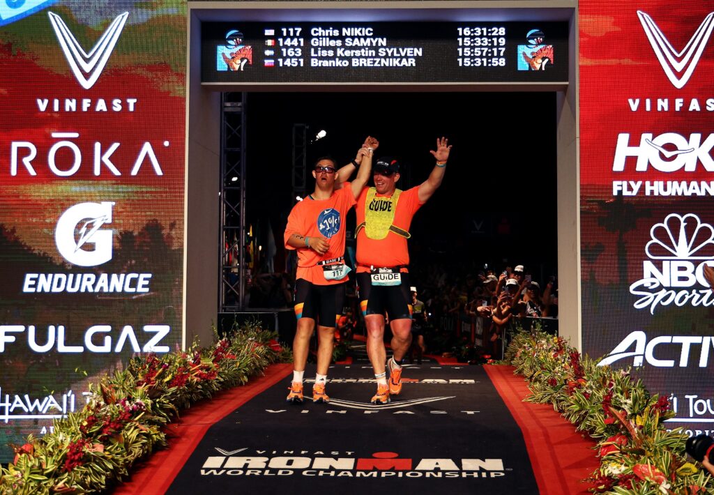 Chris Nikic and his race guide, Dan Grieb, celebrate crossing the finish line at the IRONMAN World Championship race on October 6, 2022 in Kailua-Kona, HI. (Photo by Tom Pennington/Getty Images for IRONMAN)