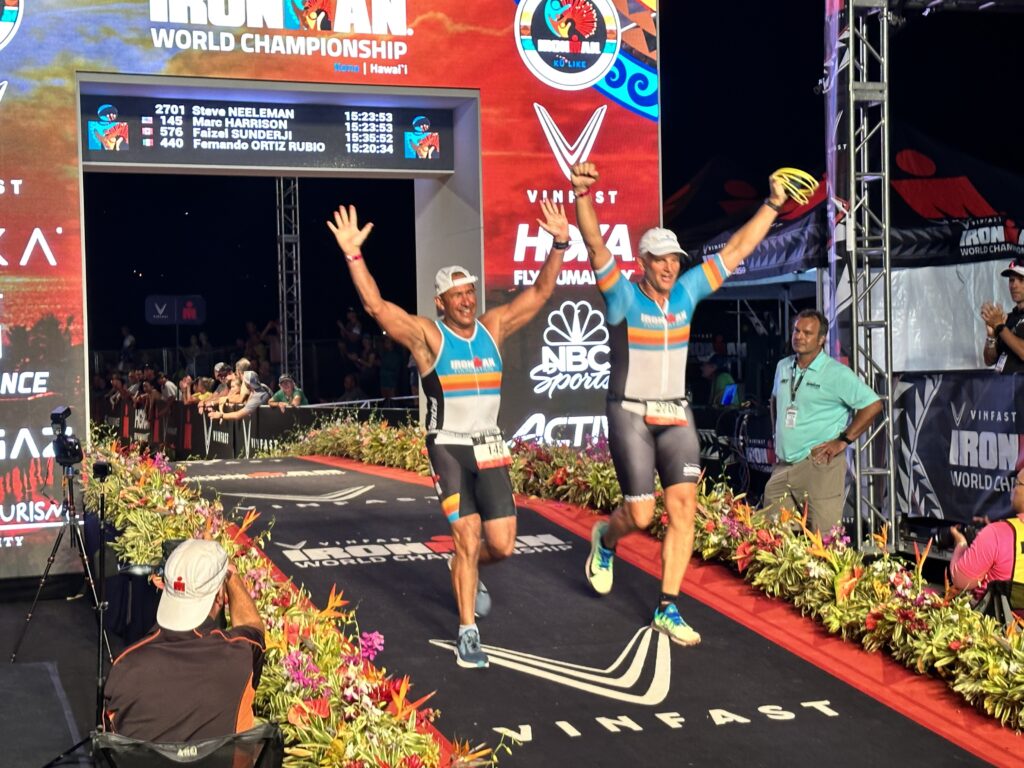 IRONMAN Foundation athletes, Marc Harrison and Steve Neeleman, cross the finish line together at the IRONMAN World Championship on October 8, 2022 in Kailua-Kona, HI. 