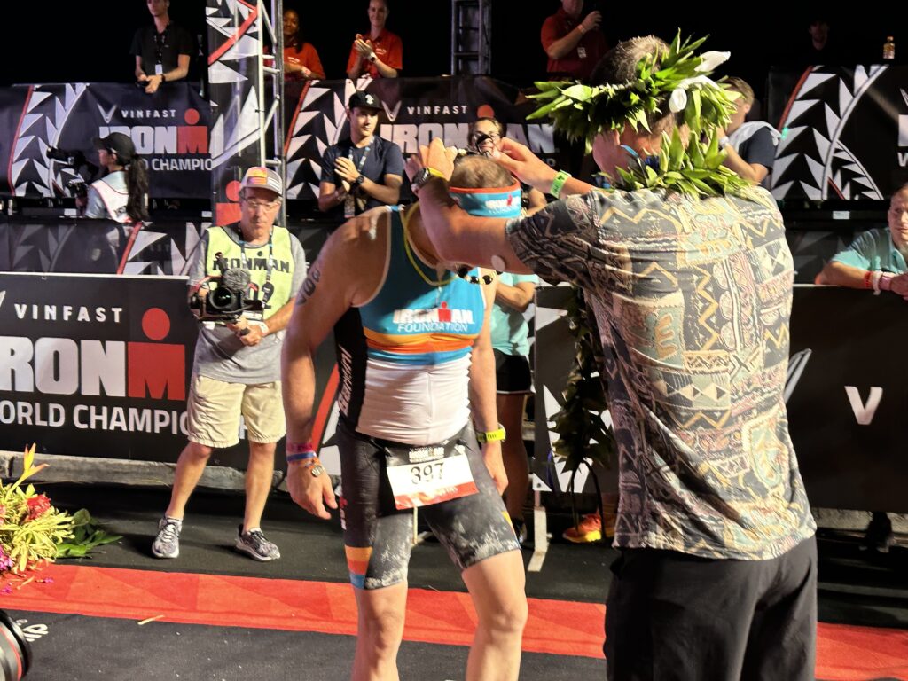 IRONMAN Foundation athlete receives his lei from 2022 IRONMAN World Championship Winner, Gustav Iden, after crossing the finish line of the IRONMAN World Championship on October 8, 2022 in Kailua-Kona, HI.